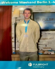 Chris Faderl beim Fulbright Welcome Weekend in Berlin vor einer Fulbright-Germany-Wand