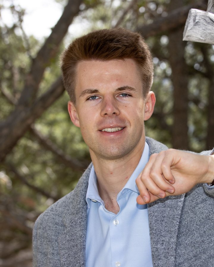 Porträt von Chris Faderl im Sakko, im Freien vor Bäumen aufgenommen