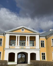 Historisches Hochschulgebäude in Estland mit gelber Fassade, weißem Säulenportikus und Rundbogendurchfahrt